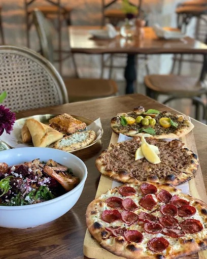 A table of flatbreads, salad, pastries, and Middle Eastern dishes at Ammatoli in Long Beach