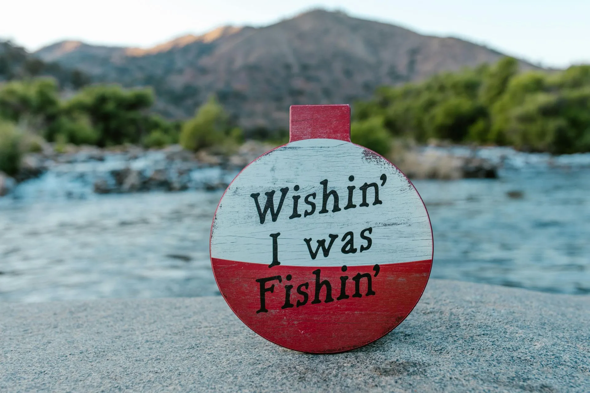 Fishing sign by the water with mountains in the distance